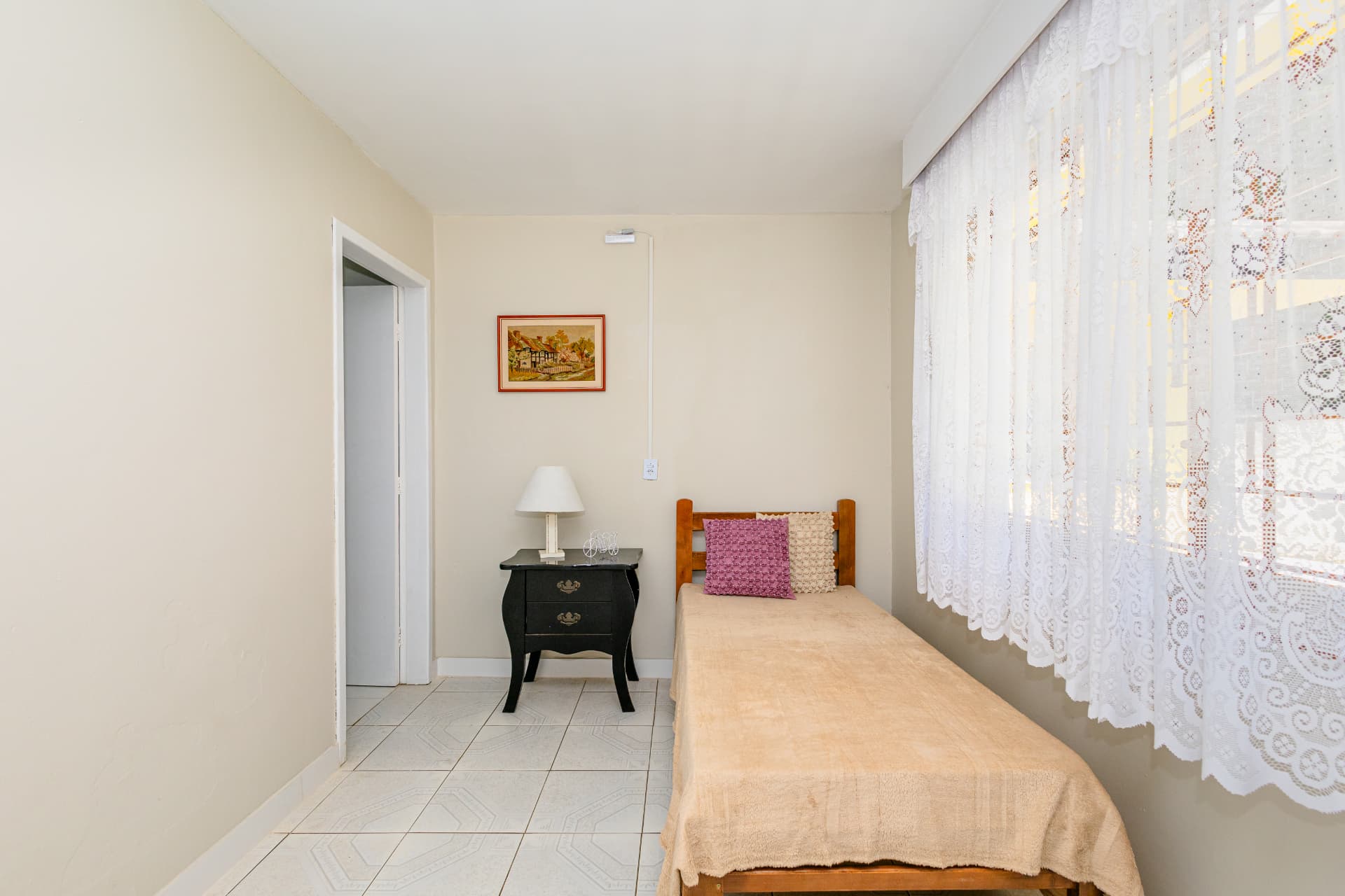Quarto individual com cama, criado-mudo e abajur