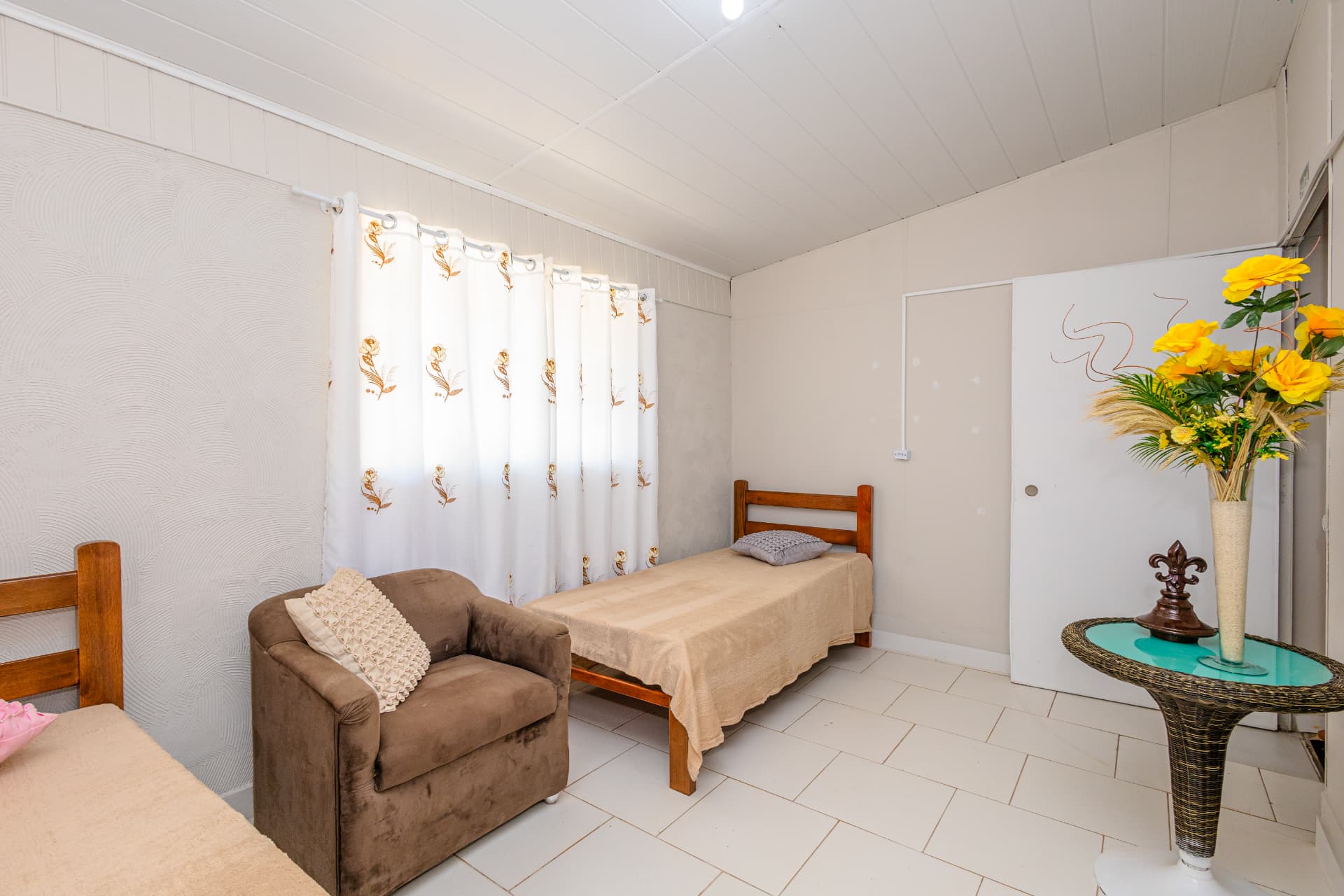 Quarto com cama individual, poltrona e mesa decorada