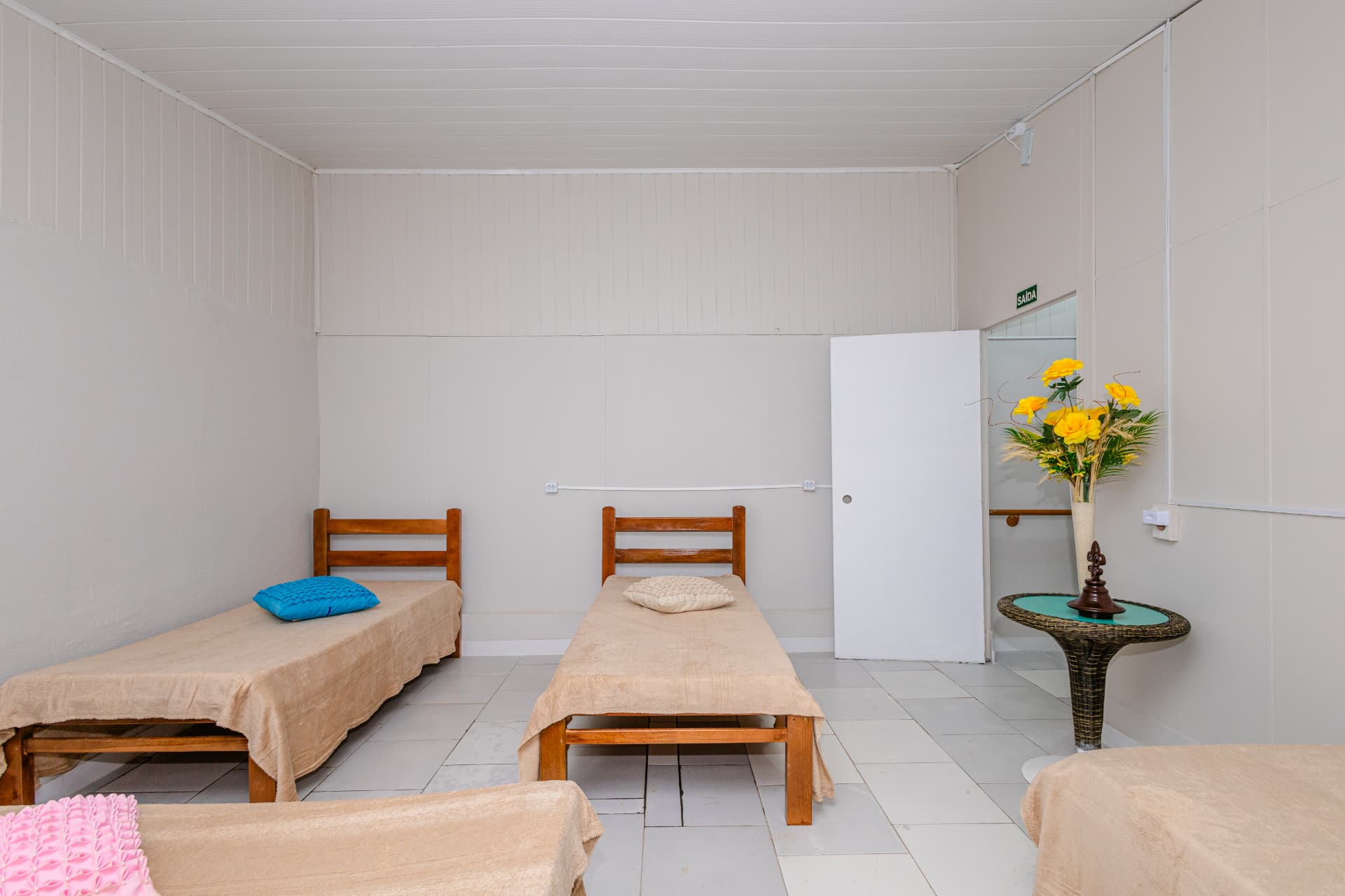 Outro ângulo do quarto compartilhado, com camas e saída sinalizada
