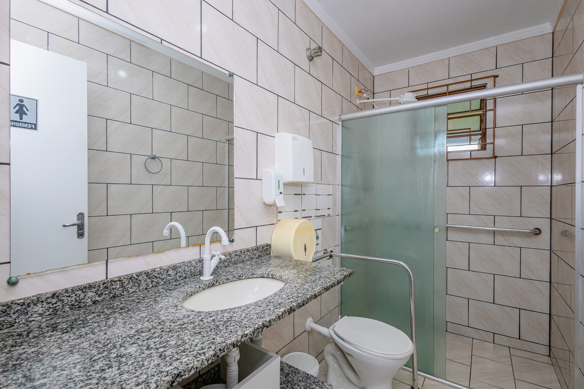 Banheiro com bancada de granito, espelho e box com barra de apoio