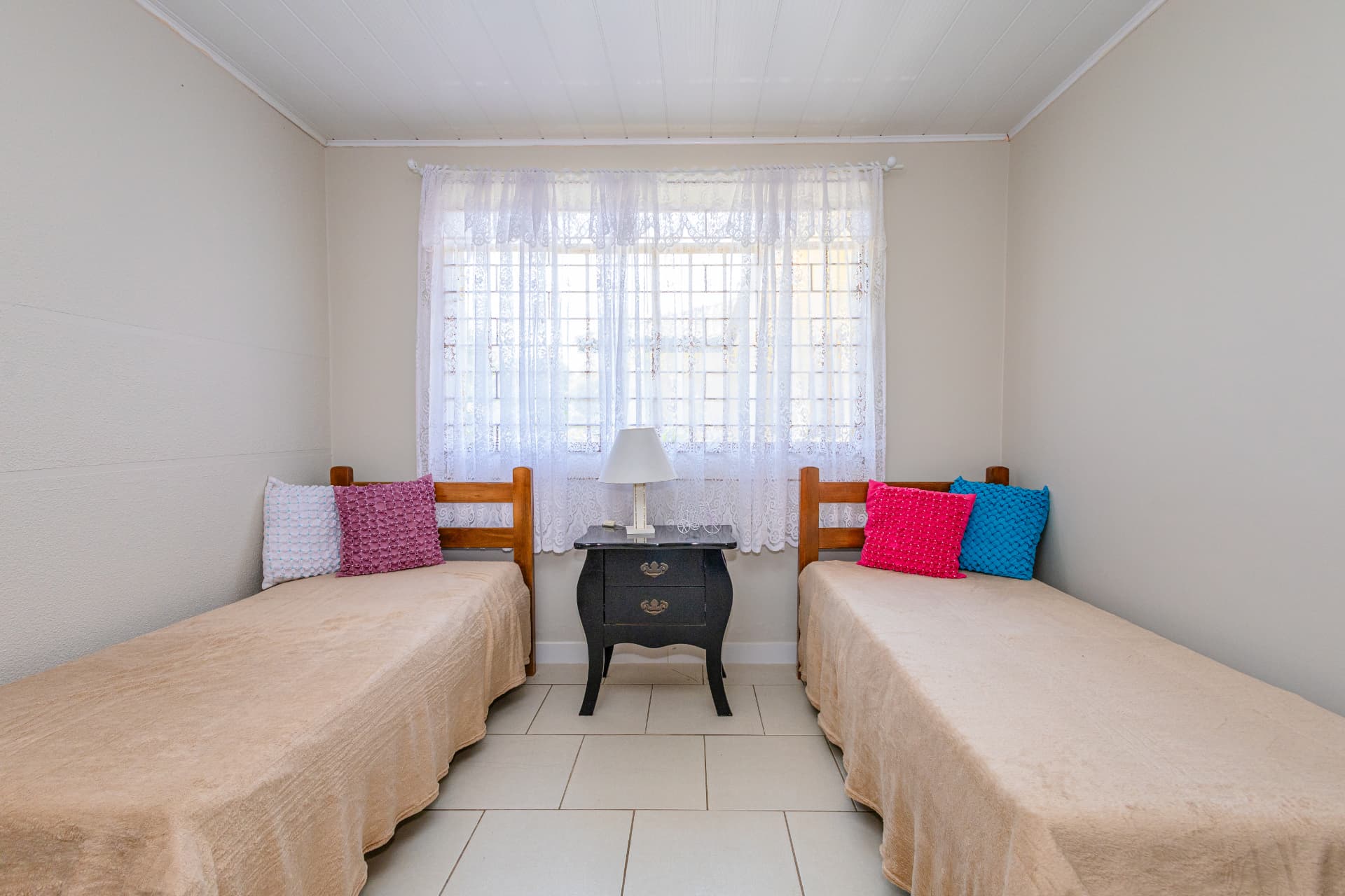 Quarto com duas camas individuais, criado-mudo e luminária
